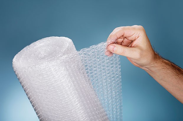 Image of a hand unrolling bubble wrap roll.