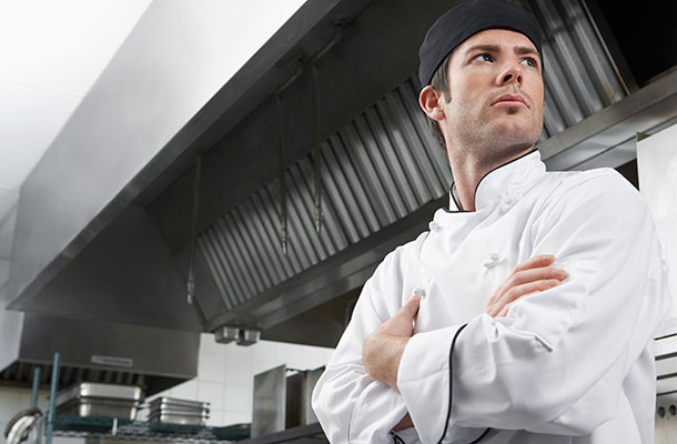 Male Chef in kitchen with arms folded.