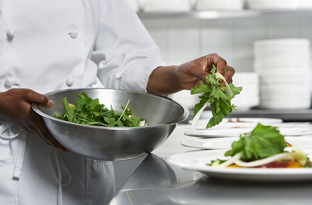 A Chef dressing a dish with salad.