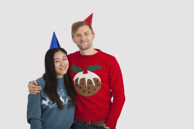 Portrait of happy multiethnic couple wearing party hats at home.