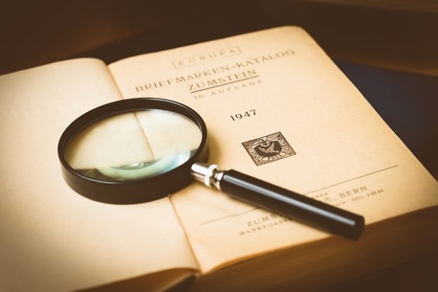 Magnifying glass with old stamp collection book.