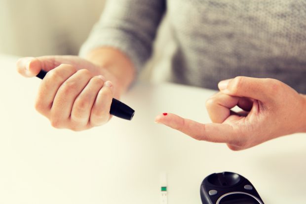 woman checking blood sugar level by glucometer at home