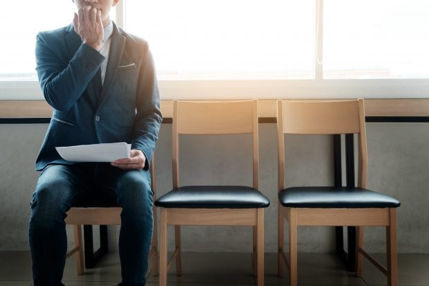 young businessman in waiting room for job interview looking anxious