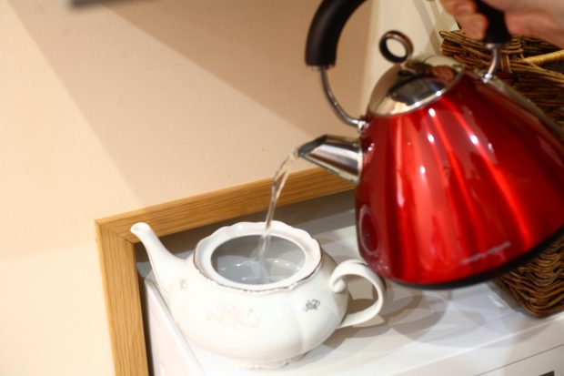 Electric kettle pouring hot water into a teapot