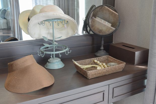 white hat and jewelry set on a dresser table in a contemporary room.