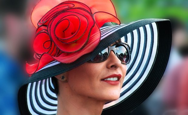 A lady wearing a designer black, white and red hat.