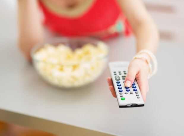 Closeup on tv remote control in hand of young woman