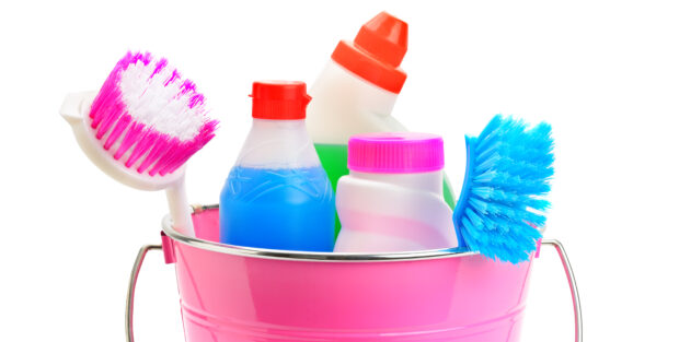 Set of household chemicals, bucket and brushes for cleaning isolated on white background. Wide photo.