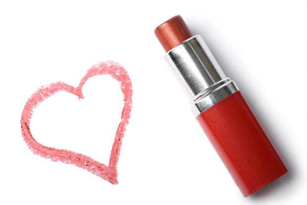 Red lipstick and love heart drawn with lipstick on white background
