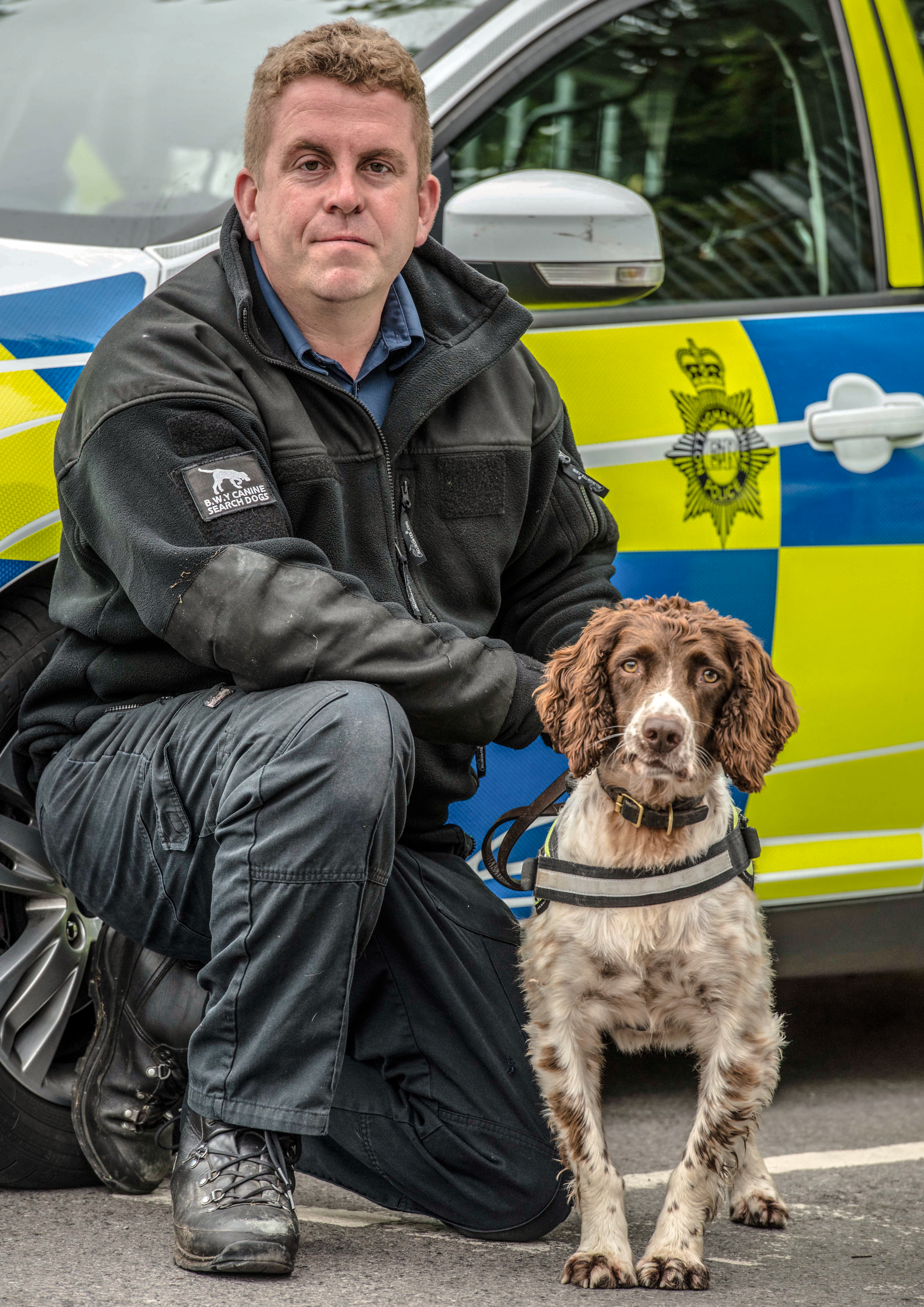 Stuart Phillips and Scamp the sniffer dog in front of a police car.