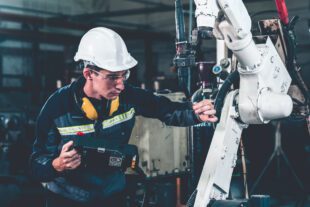 Young factory worker working with adept robotic arm