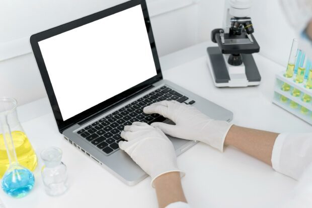 Person typing on laptop wearing white gloves