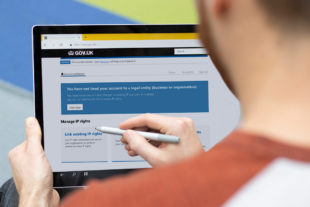 Back of a man's head and shoulders as the uses a digital pen to navigate the IPO website