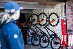 Hornit's bike rack, CLUG, holding several bikes upright in garage with person onlooking