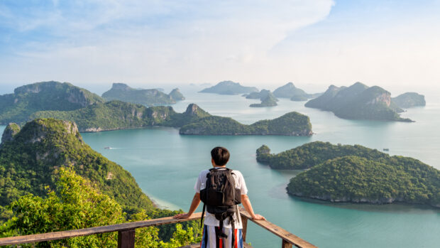 A man with a backpack looking over an island viewpoint