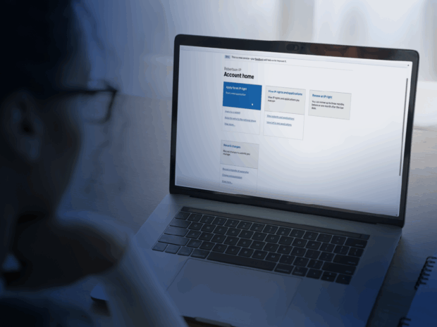 An image of a person looking at a laptop screen. It shows a gov.uk web page with 'your account'.