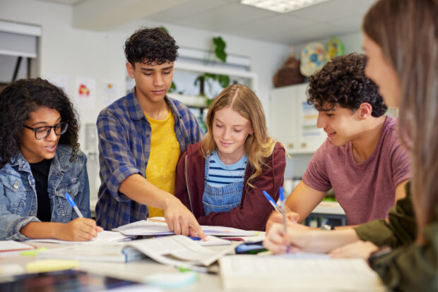 An image of a group of teenagers collaborating during a study session in classroom. 