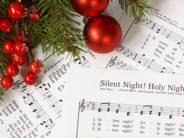 An image of Christmas Carol Sheet music with Christmas decorations on it