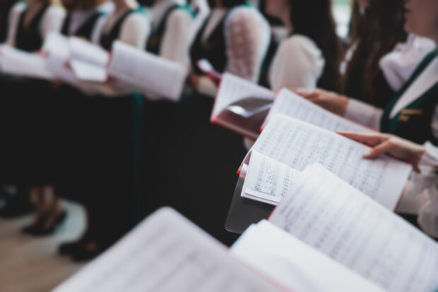 A side angle shot of a choir singing with sheet music
