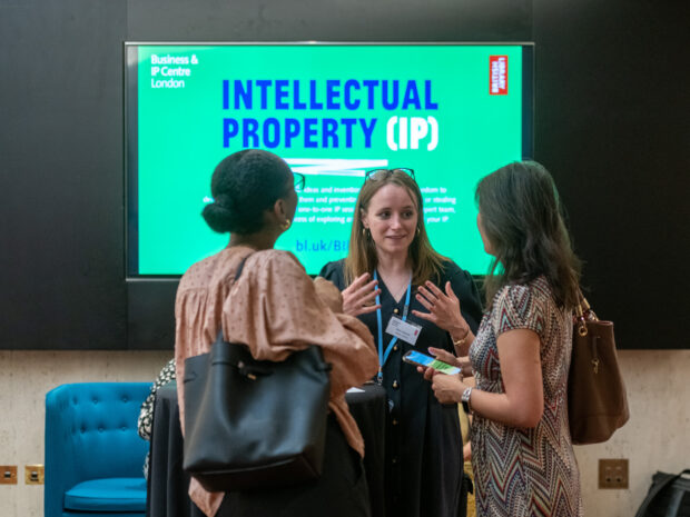 Image shows a BIPC staff member talking to two people in front on a screen that reads Intellectual Property (IP)
